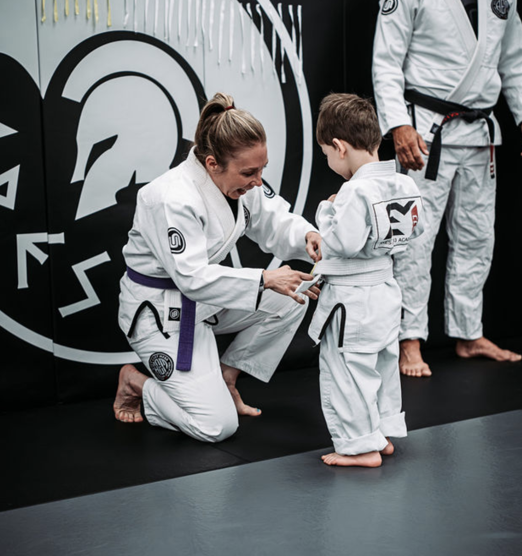 Coach tying a child's belt at Ares East Mesa